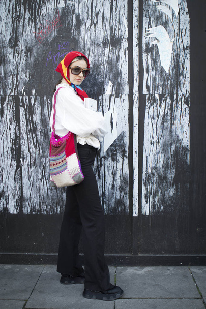 LONDON, United Kingdom- SEPTEMBER 14 2018: People on the street during the London Fashion Week. The girl in sun-protective glasses, in a red scarf, a white blouse and black trousers. - Valokuva, kuva