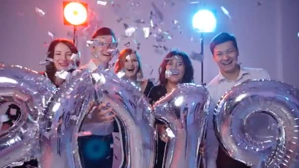 New year 2019 concept. Group of cheerful young people holding number balloons, showered with confetti - Footage, Video