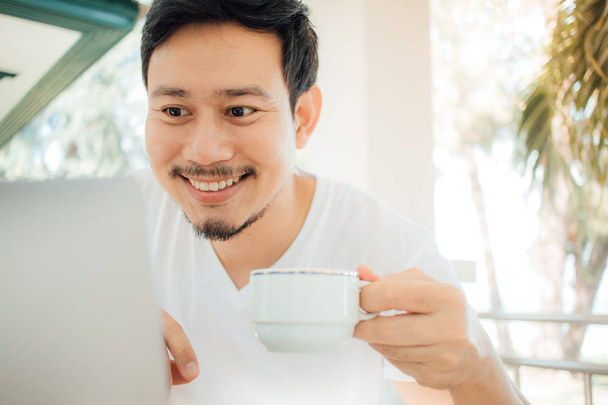 Happy Asian man drink coffee while working with computer. - Zdjęcie, obraz