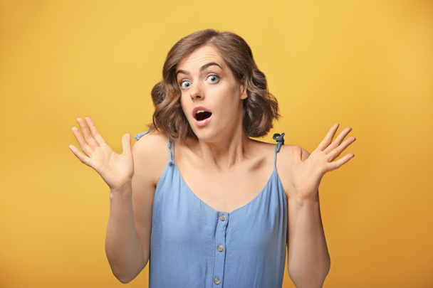 Portrait of surprised young woman on color background - Foto, Imagen