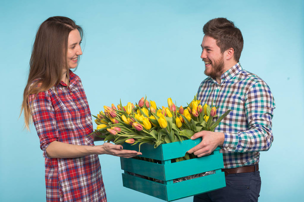 Happy květinářství oprava tulipány v velkou dřevěnou bednu na modrém pozadí. - Fotografie, Obrázek