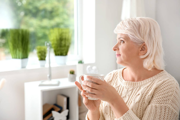 Beautiful mature woman drinking coffee at home - Foto, Bild