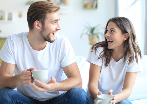 Cheerful young couple in the morning at home in the living room and laughing. - Foto, immagini