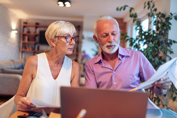 Senior couple using laptop for online payments - Foto, imagen