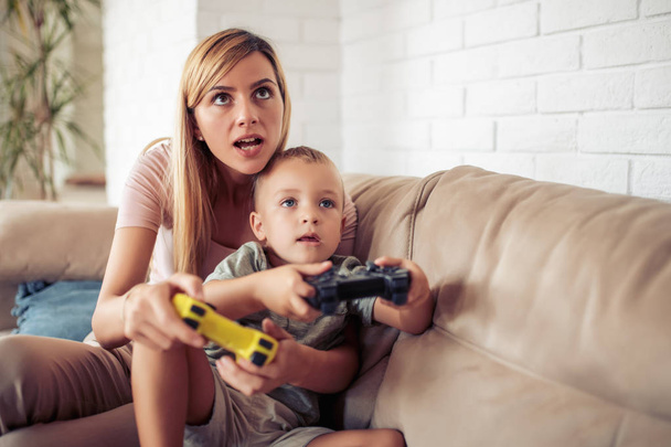 Jovem mãe feliz e seu filho jogando jogos de vídeo juntos
. - Foto, Imagem