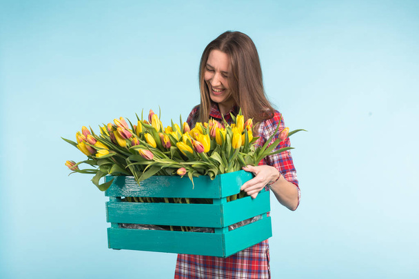 Mulher feliz rindo no estúdio com caixa de flores a mãos
 - Foto, Imagem