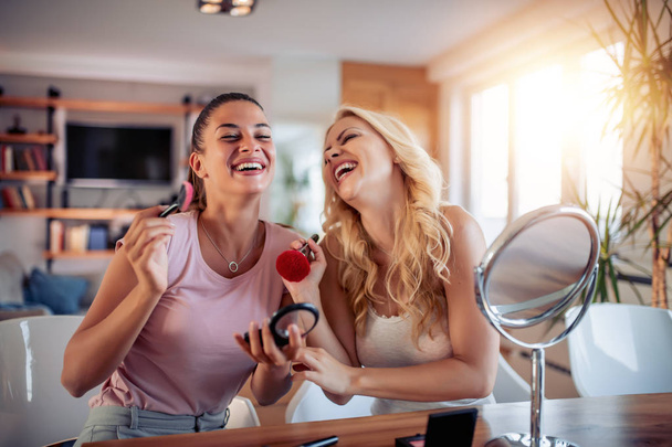 Δύο κορίτσια ευτυχισμένη εφαρμογή μακιγιάζ στο σπίτι, να διασκεδάσουμε μαζί. - Φωτογραφία, εικόνα