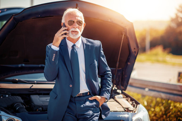 Senior businessman calling for assistance with car broken down by roadside - Zdjęcie, obraz