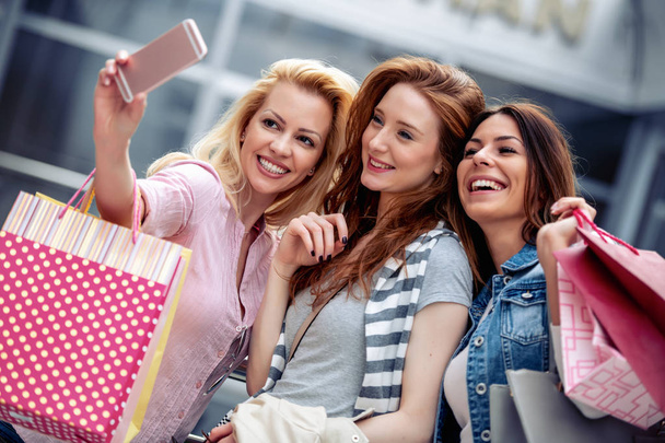 felici amiche con shopping bag a piedi in città
 - Foto, immagini