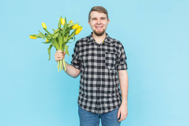 Homme tenant des tulipes jaunes sur fond bleu
 - Photo, image