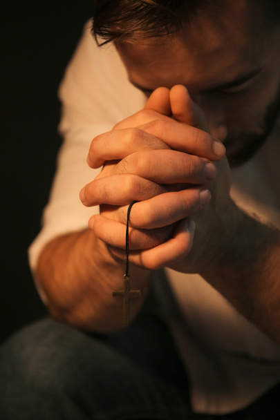 Uskonnollinen nuori mies rukoilee Jumalaa mustalla pohjalla, lähikuva
 - Valokuva, kuva