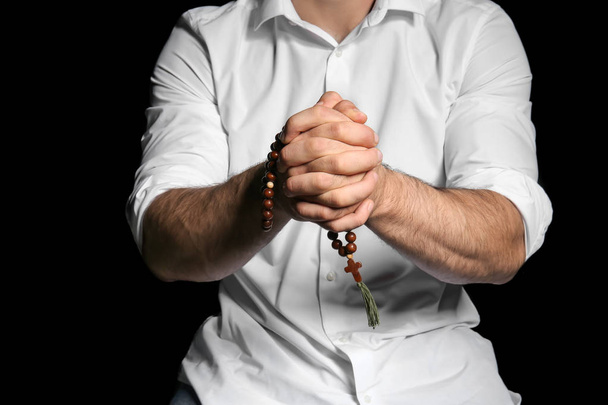 Религиозный молодой человек молится Богу на черном фоне, крупным планом
 - Фото, изображение