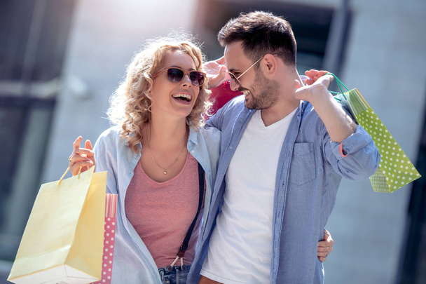 Cheerful couple with shopping bags in city - Photo, Image