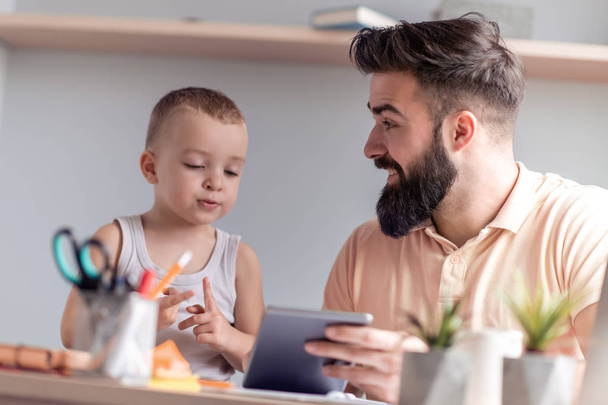 Sorridente padre e figlio guardando tablet digitale sul tavolo
. - Foto, immagini
