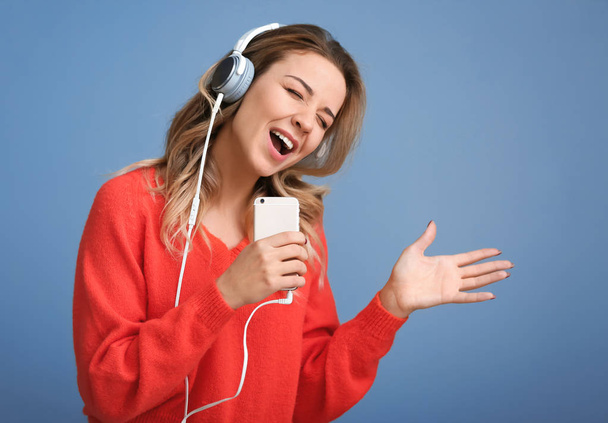 Портрет красивой молодой женщины, слушающей музыку на цветном фоне
 - Фото, изображение