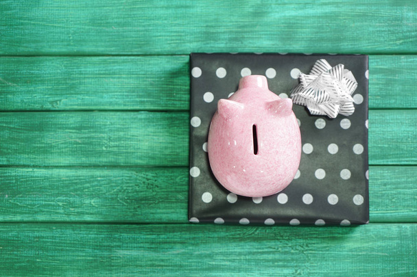 Piggy bank en de doos van de gift op houten achtergrond in kleur. Concept van het besparen van geld voor dit moment - Foto, afbeelding