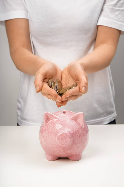 Woman putting coins into piggy bank on table - Photo, Image
