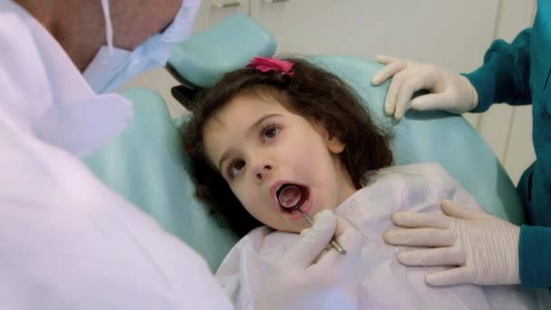 Dentist working with assistant, checking teeth of young baby girl - Video, Çekim