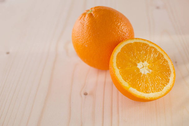 Close up of whole and halved oranges on wooden background - Foto, Imagem