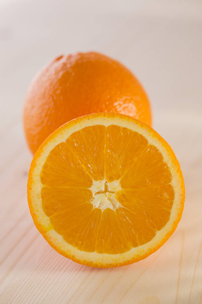 Close up of whole and halved oranges on wooden background - Valokuva, kuva