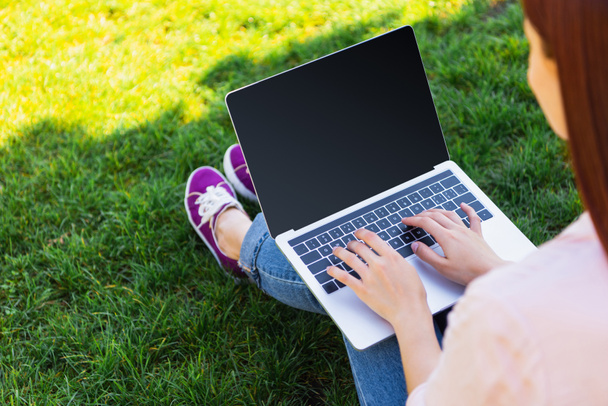 cropped image of freelancer using laptop with blank screen in park - Foto, afbeelding