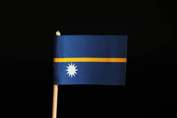 Oficjalna flaga Nauru na drewniany kij na czarnym tle. Nauru jest wyspa Państwa i należy do Oceanii. Ocean spokojny - Zdjęcie, obraz