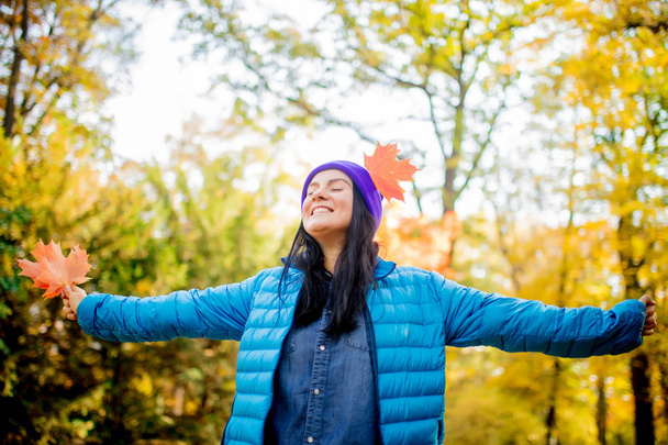 Kaunis nuori nainen sinisessä takissa ja violetti hattu lehtiä syksyllä puistossa
 - Valokuva, kuva