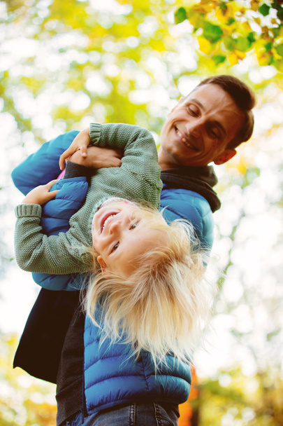 Jeune père faisant l'avion de sa fille, s'amusant dans le parc. Heure d'automne
.  - Photo, image
