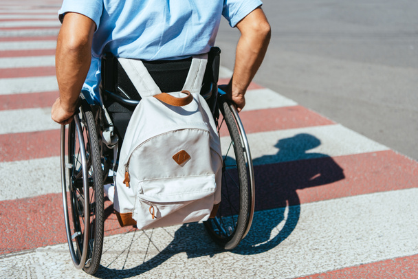 levágott kép kerekesszék fogyatékkal élő ember lovaglás a crosswalk táska - Fotó, kép