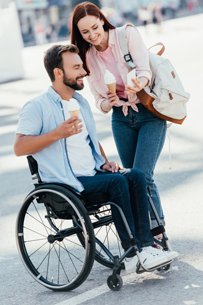 tyttöystävä jäätelöä osoittaa jotain älypuhelimeen komea poikaystävä pyörätuolissa kadulla
 - Valokuva, kuva