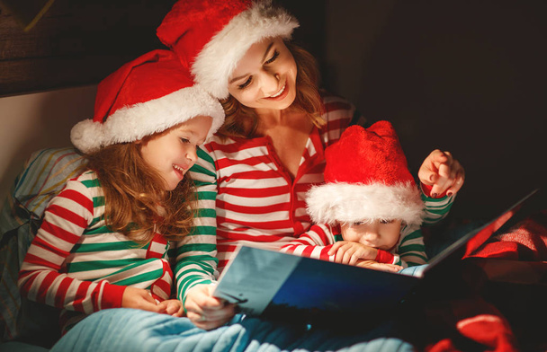 Merry Christmas! family mother reads to children a book before bed in be - Foto, imagen