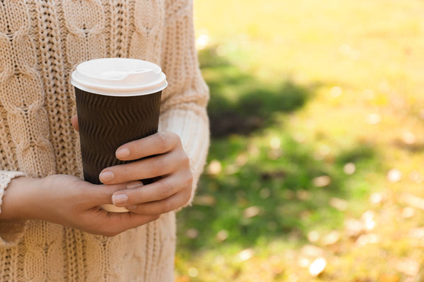 Woman holding takeaway cup with coffee outdoors - Foto, Imagen