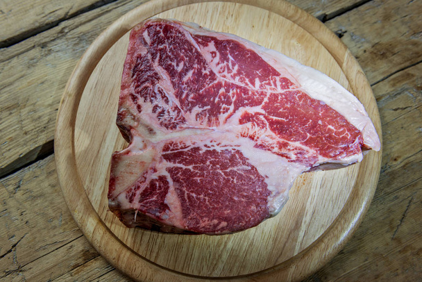 Placa de corte de madeira redonda com carne de porco crua na mesa de madeira
 - Foto, Imagem