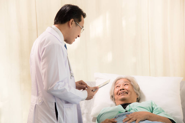 Jovem médico tem um tratamento para a paciente idosa no leito doente
, - Foto, Imagem