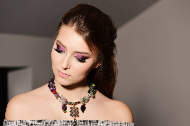 Style and fashion concept: model with colourful necklace looking down - Fotó, kép