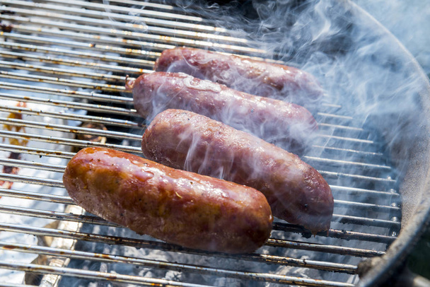 Four Sausages cook on the grill of barbecue - Photo, Image