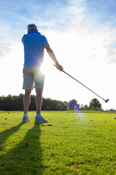 homem sênior jogando golfe no gramado verde na alemanha do sul ao pôr do sol com raios de sol brilhando
 - Foto, Imagem