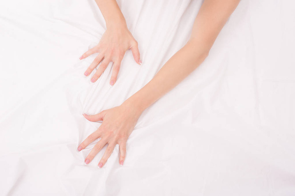 Female hands crumple white sheet, woman making sex, focus on hands - Foto, Imagen