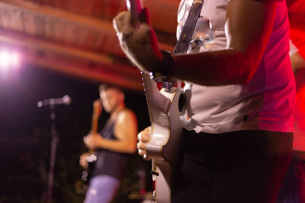Гитаристы на сцене с ярким ярким светом ламп на заднем плане
 - Фото, изображение