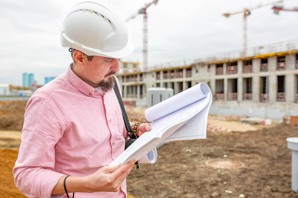 Portrait of architect at work with helmet in a construction site,reads the plan. - Foto, Imagen