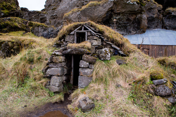Típicas casas de hielo cubiertas de hierba. Casas de césped islandés cubiertas de hierba y acantilados en el fondo. hermosas casas escandinavas
. - Foto, imagen