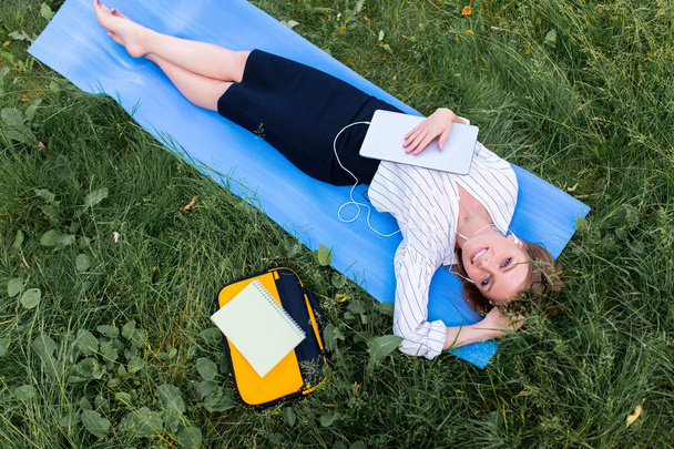 Woman resting in the park lying on the grass with a laptop and listening to music - Foto, immagini