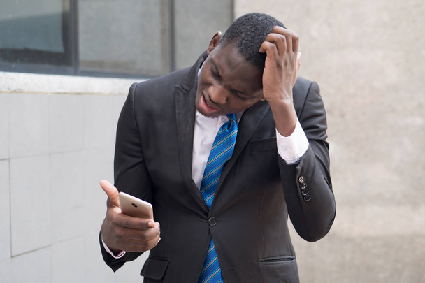 hombre de negocios africano molesto usando teléfono inteligente; retrato de hombre de negocios negro molesto, infeliz, enojado, frustrado hablando a través de su teléfono inteligente, concepto de acuerdo de éxito; modelo de hombre africano adulto joven
 - Foto, imagen