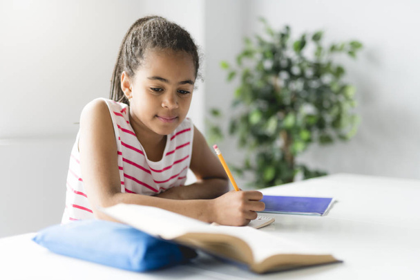 A cute Black girl doing homework at home - Fotó, kép