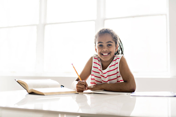 A cute Black girl doing homework at home - Fotoğraf, Görsel