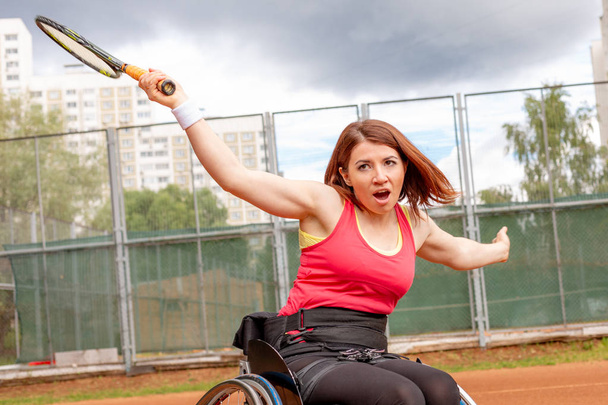 Tekerlekli sandalye tenis kortunda tenis oynamaya Engelli genç kadın. - Fotoğraf, Görsel