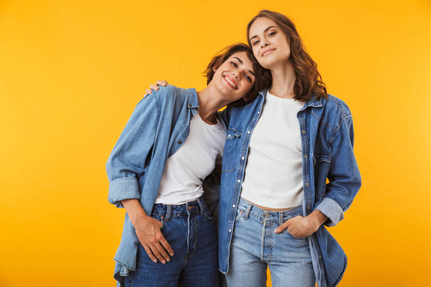 Image of happy emotional young women friends posing isolated over yellow background. - Foto, imagen