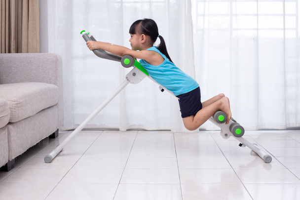 Asiática chinesa menina jogando máquina de treino na sala de estar em casa
 - Foto, Imagem
