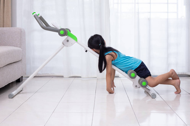 Asian Chinese little Girl playing workout machine in the living room at home - Photo, Image