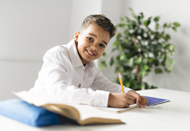 A cute Black boy doing homework at home - Фото, зображення
